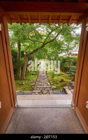 La vue à travers la porte en bois au jardin avec la route en pierre. Kyoto.Japon Banque D'Images