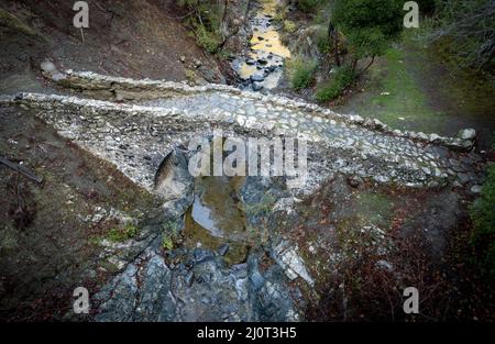 Drone aérien pittoresque d'un pont lapidé médiéval avec de l'eau qui coule dans la rivière.Elia Bridge Troodos chypre Banque D'Images