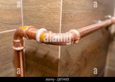 Coude de tuyau en cuivre pour les installations au gaz naturel, fixé à un mur dans une chaufferie bordée de carreaux de céramique. Banque D'Images