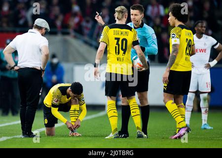 20 mars 2022, Rhénanie-du-Nord-Westphalie, Cologne: Football: Bundesliga, 1. FC Köln - Borussia Dortmund, Matchday 27, RheinEnergieStadion: Jude Bellungham de Dortmund (2nd de gauche) met calmement de nouvelles chaussures de football sous l'œil vigilant de l'entraîneur de Cologne Steffen Baumgart (l), à côté de lui l'arbitre Daniel Siebert qui parle à Marius Wolf (M) de Dortmund. Photo: Rolf Vennenbernd/dpa - NOTE IMPORTANTE: Conformément aux exigences du DFL Deutsche Fußball Liga et du DFB Deutscher Fußball-Bund, il est interdit d'utiliser ou d'utiliser des photographies prises dans le stade et/ou du match dans la forme Banque D'Images