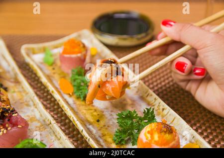 Femme mangeant de délicieux sushi gunkan, en gros plan sur des baguettes Banque D'Images