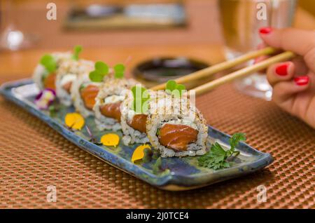 Femme mangeant de délicieux sushi gunkan, en gros plan sur des baguettes Banque D'Images