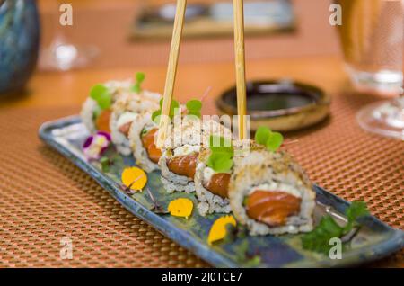 Femme mangeant de délicieux sushi gunkan, en gros plan sur des baguettes Banque D'Images