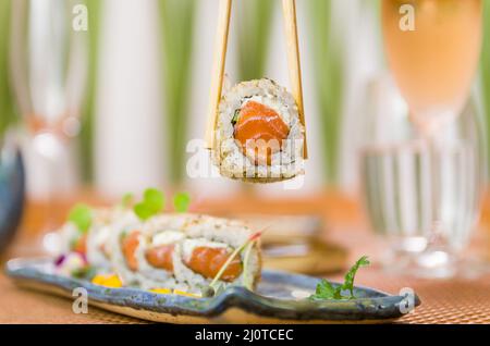 Femme mangeant de délicieux sushi gunkan, en gros plan sur des baguettes Banque D'Images