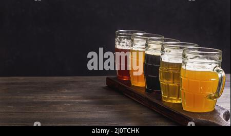 Ensemble de dégustation de différents types de bière sur une table sur fond sombre avec espace de copie Banque D'Images