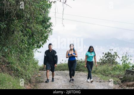 trois jeunes latinos vont pour une randonnée matinale sur un sentier à travers les montagnes colombiennes, observant la belle nature de la région de eje cafetero, dans Banque D'Images