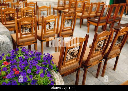 Les chaises en bois avec des motifs sur le dos se tiennent en rangées sur des pavés Banque D'Images