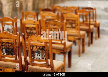 Les chaises en bois avec des motifs sur le dos se tiennent en rangées Banque D'Images