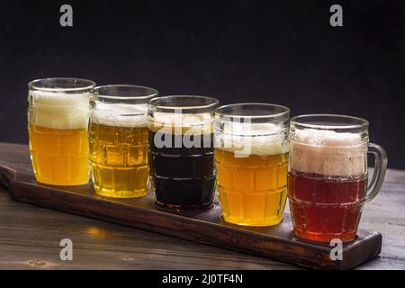 Ensemble de dégustation de différents types de bière sur une table sur fond sombre Banque D'Images