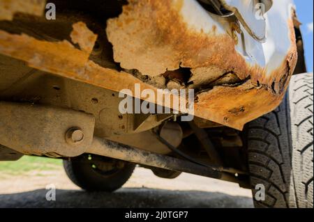 Travaux de réparation et de soudage de la carrosserie requis. Rouille sur une vieille voiture grise. Trou de rouille sur une ancienne surface métallique peinte usée. Banque D'Images