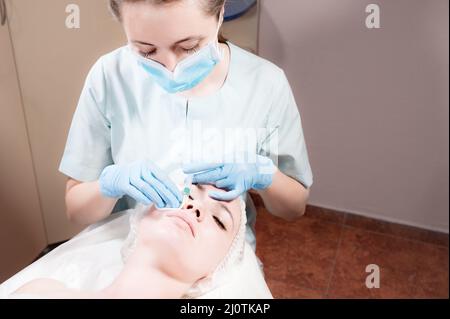 Jeune femme caucasienne recevant une injection de botox dans la joue d'une esthéticienne professionnelle dans un salon de beauté Banque D'Images