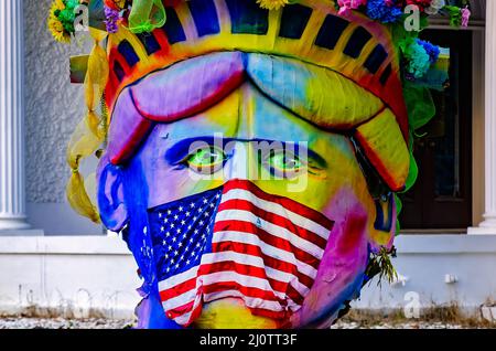 Un propriétaire d'une maison fait une déclaration politique avec des décorations de Mardi gras, avec la Statue de la liberté portant un drapeau américain comme masque facial et museau. Banque D'Images