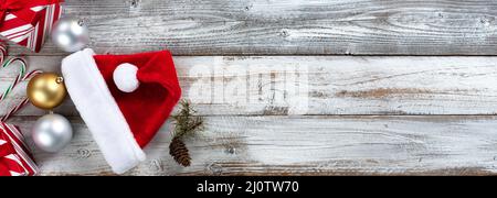 Boules de Noël traditionnelles en argent et or avec cadeaux, chapeau de Père Noël, Cannes de bonbons et cônes de pin sur fond de bois blanc avec espace de copie Banque D'Images