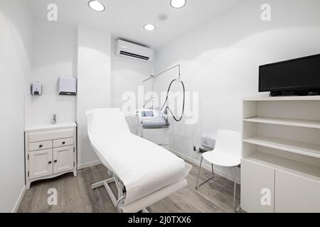 Cabine avec une table couverte de papier dans une clinique de beauté avec un appareil pour les soins de la peau et de drainage Banque D'Images