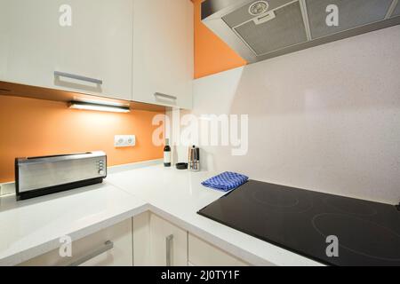 Coin cuisine avec un comptoir en pierre blanche et des murs orange avec une plaque vitrocéramique, une cafetière et un grille-pain sur le comptoir Banque D'Images