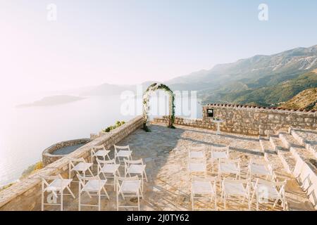 L'arche de mariage se dresse sur une terrasse d'observation au-dessus de la mer, devant des rangées de chaises blanches Banque D'Images