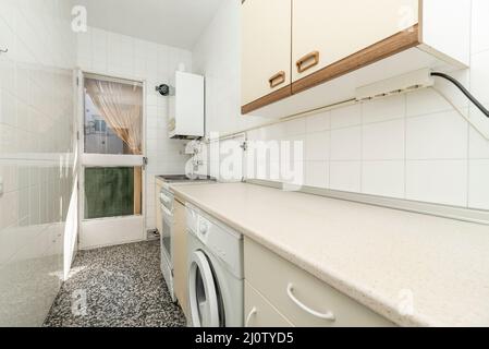 cuisine ancienne avec une porte en bois donnant sur une terrasse, un chauffage au gaz naturel et des planchers en terrazzo, un comptoir rose doux et des touches de bois sur les armoires Banque D'Images