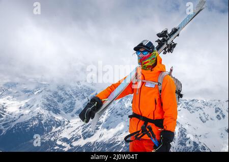 Portrait d'un athlète skieur avec des skis sur son épaule et un sac à dos sur son dos. Escalade des montagnes enneigées avec ski Banque D'Images