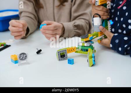 Des enfants multiethniques à la LEÇON STEM construire un robot dans une salle de classe avec une femme enseignante les enfants font un modèle de bras électronique à l'école de science moderne Banque D'Images