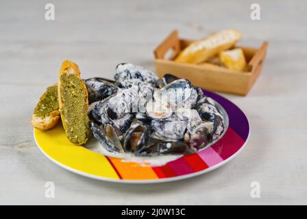 moules dans une sauce crémeuse sur une assiette avec chebata et sauce pésta. Banque D'Images