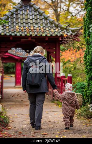 Un jeune enfant avec une femme marche dans le parc Banque D'Images