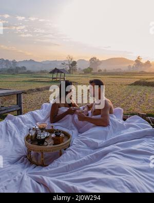 Couple homme et femme au lit regardant sur le champ de rizières dans le nord de la Thaïlande Nan Banque D'Images