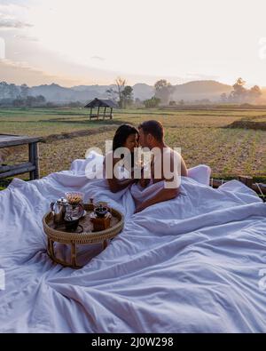 Couple homme et femme au lit regardant sur le champ de rizières dans le nord de la Thaïlande Nan Banque D'Images