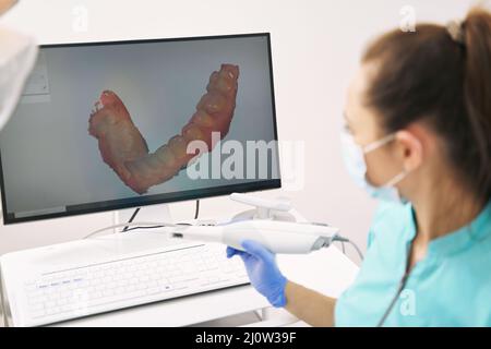 Dentiste analysant 3D acquisitions des dents du patient en clinique Banque D'Images
