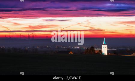 Clocher au lever du soleil illuminé au lever du soleil avec des éoliennes Banque D'Images