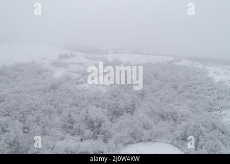 Vue aérienne par drone d'une route et d'un village isolé couvert de neige dans le nord du Portugal, Vila Real Banque D'Images