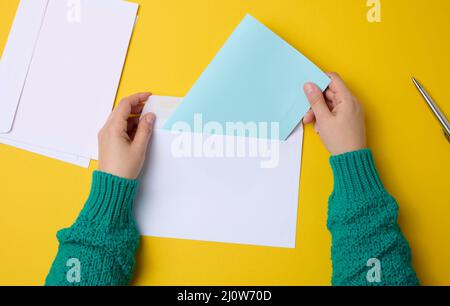Main femelle pour les enveloppes en papier blanc sur fond orange, vue de dessus. Envoi et réception de correspondance Banque D'Images