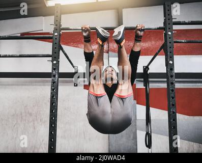 Renforcer son noyau avec quelques pull-ups. Photo d'un jeune homme qui fait des exercices dans une salle de sport. Banque D'Images