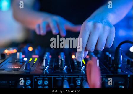 Gros plan vue de face des mains du DJ contrôlant une table de musique dans une discothèque. Banque D'Images