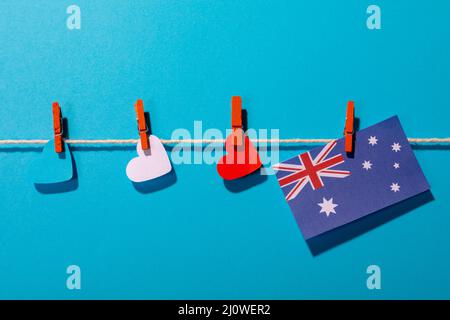 Drapeau de l'Australie avec des papiers en forme de coeur sur une corde à linge sur fond bleu avec espace pour les copies Banque D'Images