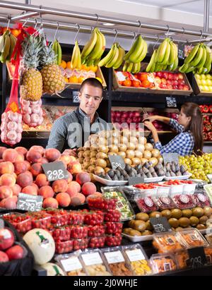 homme dans le tablier stansng près de kiwi frais et des fruits Banque D'Images