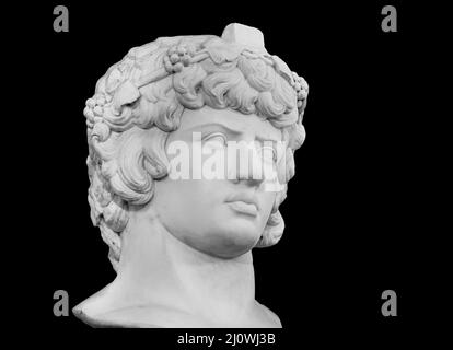 Copie en gypse de la célèbre statue antique tête d'Antinous isolée sur fond noir. Plâtre sculpture antique jeune homme visage. REN Banque D'Images