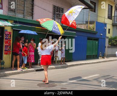 Une femme porte son drapeau philippin à l'étonnement de sa famille. Bongbong Marcos Jr. Visite les villes de Navotas et Malabo, dans le cadre des sorties de campagne de UniTeam dans le nord du Grand Manille. Il est le seul fils de l'ancien homme fort philippin, le président Ferdinand Marcos Sr. Et l'ancienne première dame Imelda Romualdez Marcos. BBM, un acronyme de Marcos Jr., est en train d'obtenir le siège le plus élevé du pays, la présidence. Alors qu'il garde sa tête dans les sondages d'opinion, son rêve est de fournir un leadership unificateur au pays s'il gagne. Banque D'Images