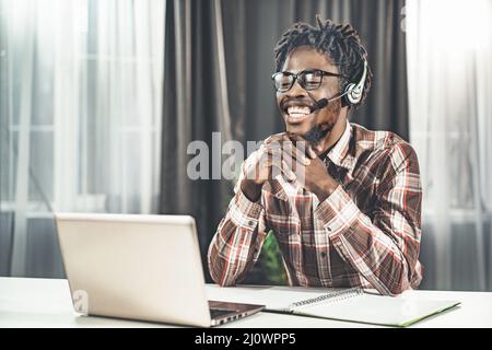 Un jeune professeur d'anglais donne une leçon de vidéo en ligne. Plan du semestre d'étude. L'homme s'assoit à la table et regarde le Banque D'Images