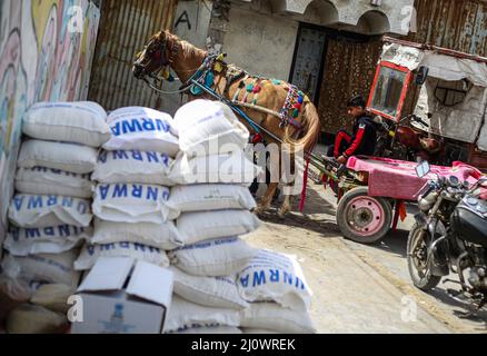 Gaza, Palestine. 20th mars 2022. Un palestinien est assis sur une voiturette à l'extérieur d'un centre de distribution d'aide géré par l'Office de secours et de travaux des Nations Unies pour les réfugiés de Palestine (UNRWA), dans le camp de réfugiés de Shati, dans la ville de Gaza. Les prix des denrées alimentaires dans la ville de Gaza ont augmenté après l'invasion russe de l'Ukraine. Certains réfugiés vendent maintenant l'aide alimentaire, qui comprend la farine, l'huile de cuisson, le riz, les lentilles, et le lait, pour obtenir de l'argent pour leur vie. (Photo de Mahmoud Issa/SOPA Images/Sipa USA) crédit: SIPA USA/Alay Live News Banque D'Images