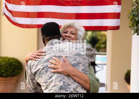 Une heureuse femme afro-américaine qui embrasse son soldat à son retour à l'entrée Banque D'Images