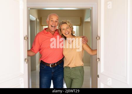 Portrait d'un couple âgé caucasien souriant tout en ouvrant la porte d'entrée de la maison Banque D'Images