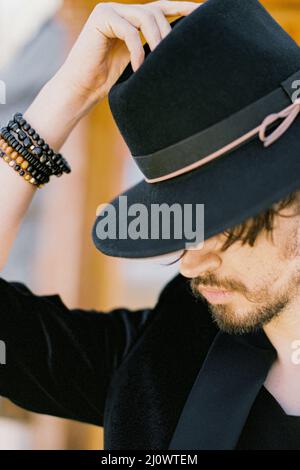 Portrait d'un jeune homme mettant un chapeau noir sur sa tête Banque D'Images