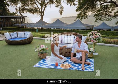 Coucher de soleil sur la plage confortable Pattaya Thaïlande , couple homme et femme regardant le coucher de soleil au bord de la piscine à Pattaya Thaïlande, couple de manger pizz Banque D'Images