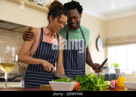 Joyeux jeune couple multiracial cuisine repas ensemble à l'île de cuisine Banque D'Images