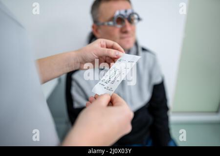 Le patient masculin subit un test oculaire et une prescription de lunettes en clinique d'ophtalmologie. Optométriste vérifiant le patient Banque D'Images