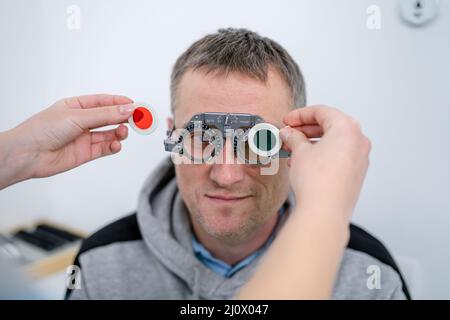 Le patient masculin subit un test oculaire et une prescription de lunettes en clinique d'ophtalmologie. Optométriste vérifiant le patient Banque D'Images