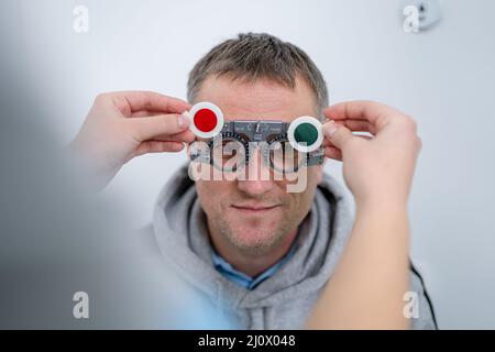 Le patient masculin subit un test oculaire et une prescription de lunettes en clinique d'ophtalmologie. Optométriste vérifiant le patient Banque D'Images