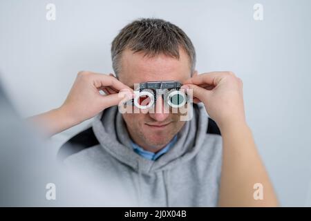 Le patient masculin subit un test oculaire et une prescription de lunettes en clinique d'ophtalmologie. Optométriste vérifiant le patient Banque D'Images