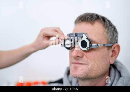 Le patient masculin subit un test oculaire et une prescription de lunettes en clinique d'ophtalmologie. Optométriste vérifiant le patient Banque D'Images