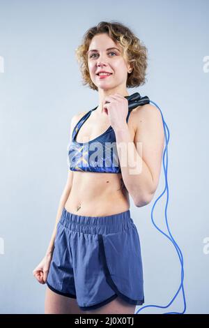 Mettre la femme en forme avec la corde de saut posé dans la salle de gym. Le sport exerce un concept de mode de vie sain. Femme sportive heureuse avec corde à sauter pos Banque D'Images